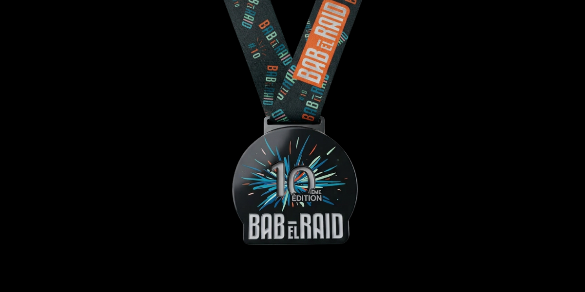 Médaille finisher Bab el Raid 2026 en métal noir avec visuel coloré pour la 10e édition du raid aventure dans le désert.